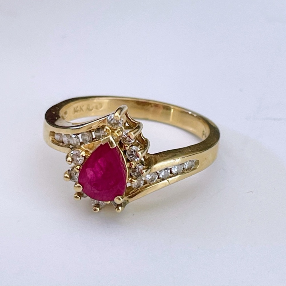 Pear cut ruby ring accented by diamonds on a 14k yellow gold band size 7